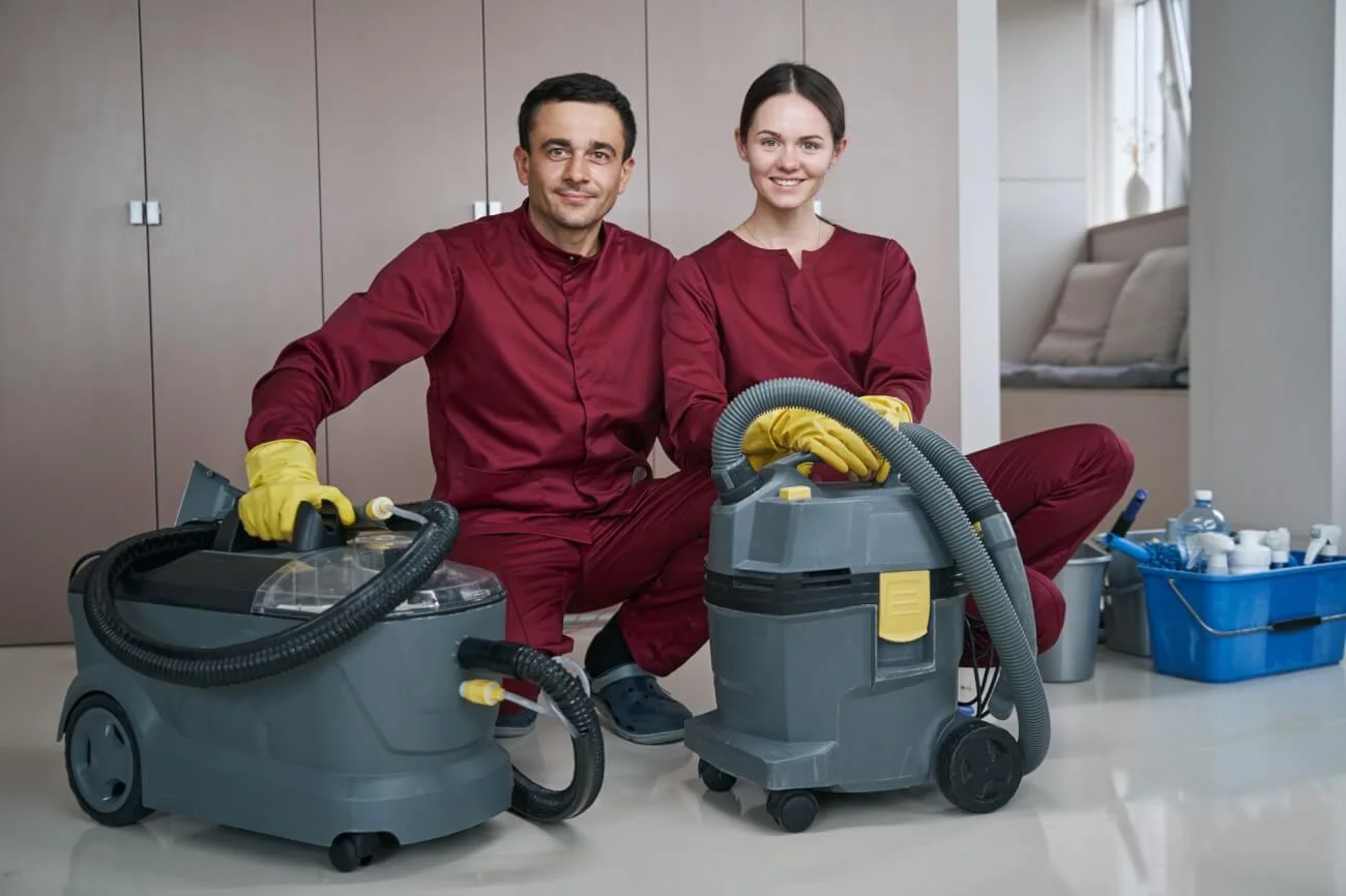 Cheerful cleaner and her colleague posing for camera before housecleaning Cheerful cleaner and her colleague posing for camera before housecleaning